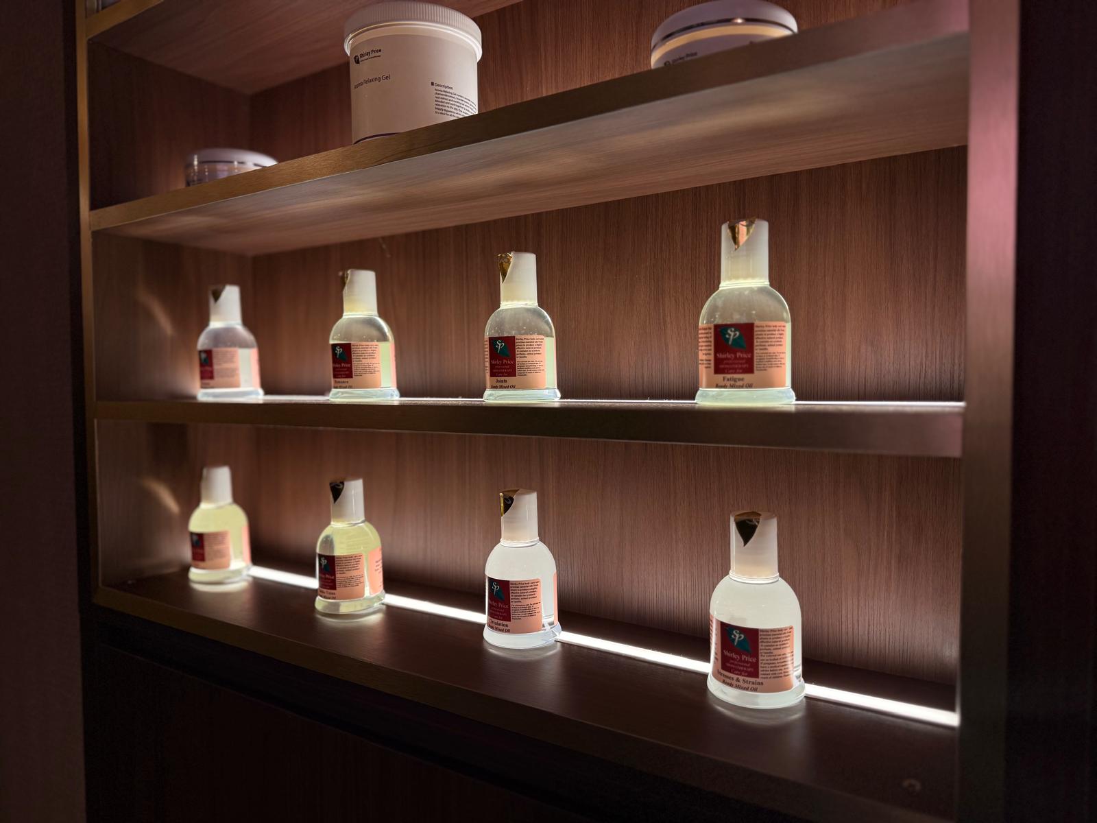Shirley Price essential oil bottles on backlit wooden shelves in the studio